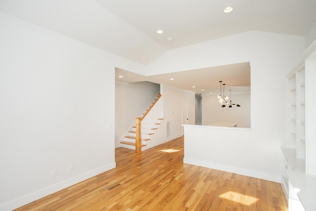 unfurnished living room featuring a chandelier, light wood-type flooring, and vaulted ceiling