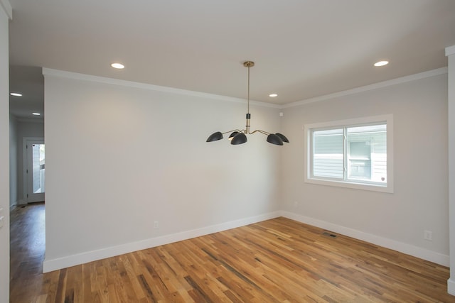 unfurnished dining area with an inviting chandelier, wood-type flooring, and ornamental molding