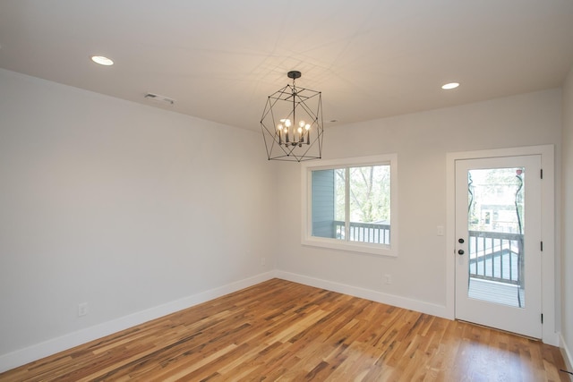 empty room featuring hardwood / wood-style floors and a notable chandelier