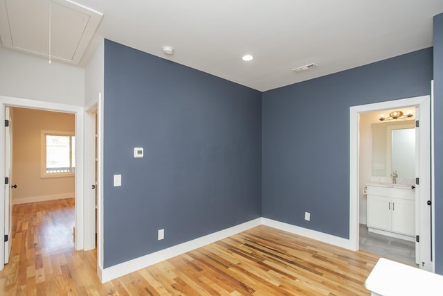 unfurnished bedroom featuring sink, connected bathroom, and light hardwood / wood-style flooring