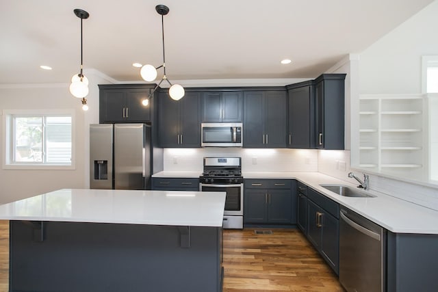 kitchen featuring pendant lighting, stainless steel appliances, a kitchen island, and sink