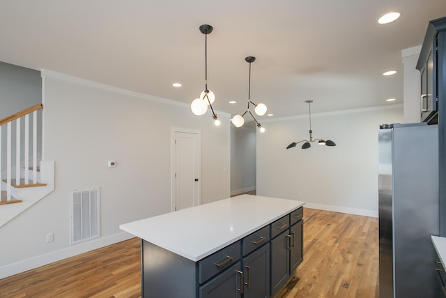 kitchen with crown molding, pendant lighting, light hardwood / wood-style flooring, a center island, and stainless steel refrigerator