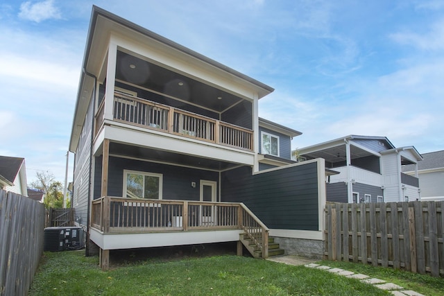 rear view of house featuring a balcony, a lawn, and central air condition unit