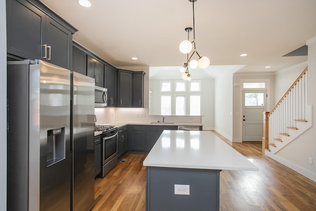 kitchen with sink, a center island, dark hardwood / wood-style flooring, pendant lighting, and appliances with stainless steel finishes