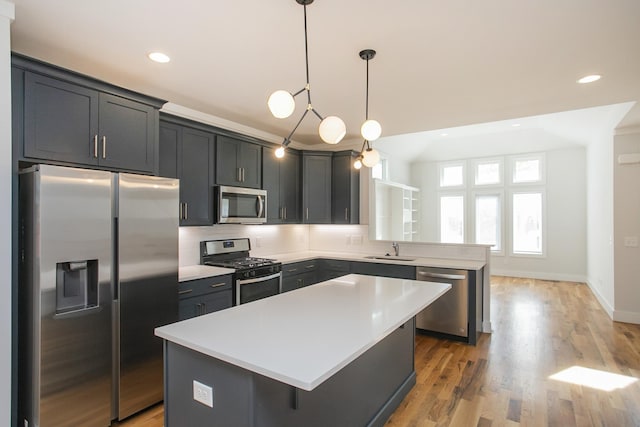 kitchen featuring sink, hanging light fixtures, stainless steel appliances, light hardwood / wood-style flooring, and a kitchen island