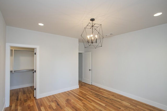 spare room with hardwood / wood-style floors and a chandelier