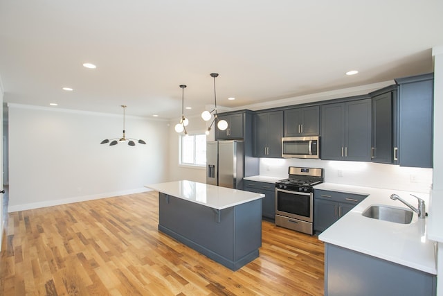 kitchen featuring light wood-type flooring, stainless steel appliances, sink, decorative light fixtures, and a center island