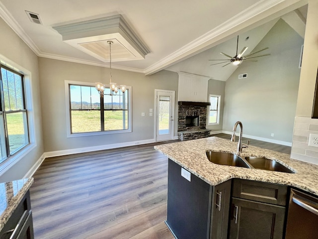 kitchen featuring light stone counters, stainless steel dishwasher, ceiling fan with notable chandelier, sink, and decorative light fixtures