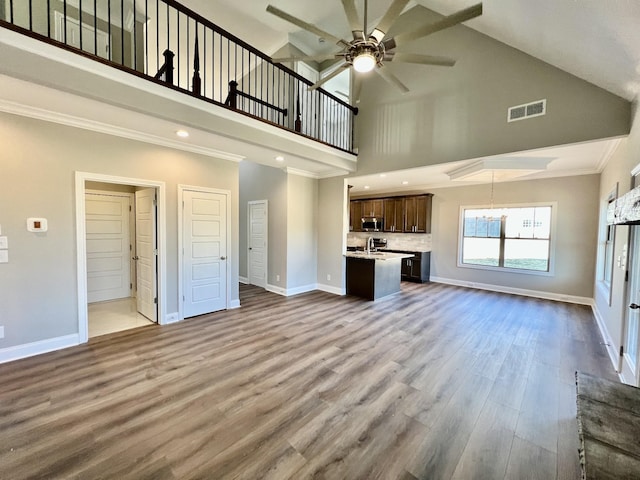 unfurnished living room featuring ceiling fan with notable chandelier, light hardwood / wood-style floors, and high vaulted ceiling