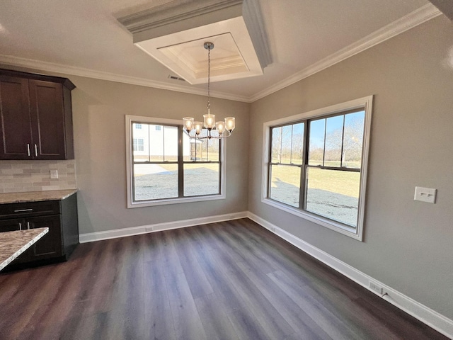 unfurnished dining area featuring plenty of natural light, crown molding, and an inviting chandelier