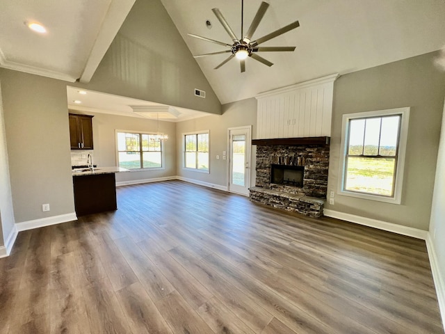 unfurnished living room featuring high vaulted ceiling, ceiling fan with notable chandelier, sink, dark hardwood / wood-style floors, and a fireplace