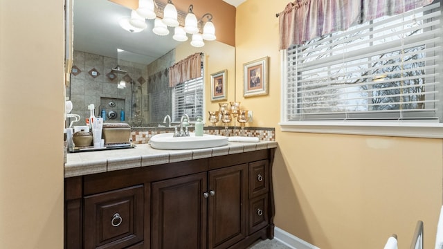 bathroom with tiled shower, vanity, and a healthy amount of sunlight