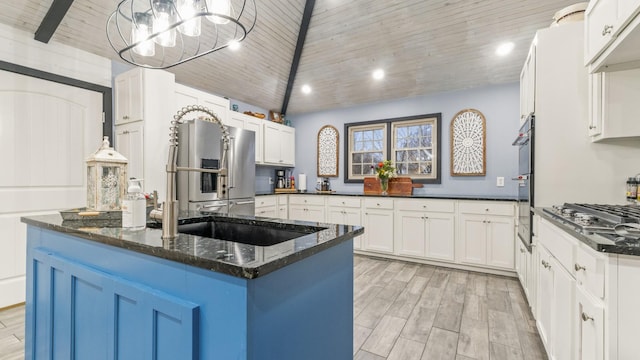 kitchen featuring pendant lighting, dark stone counters, appliances with stainless steel finishes, a kitchen island, and white cabinetry