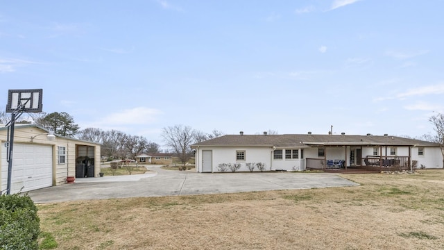 rear view of house featuring a lawn, a garage, and a wooden deck