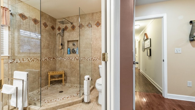 bathroom featuring tile patterned flooring, a tile shower, and toilet