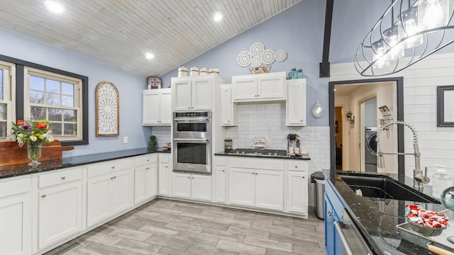 kitchen featuring white cabinets, dark stone countertops, hanging light fixtures, and stainless steel appliances