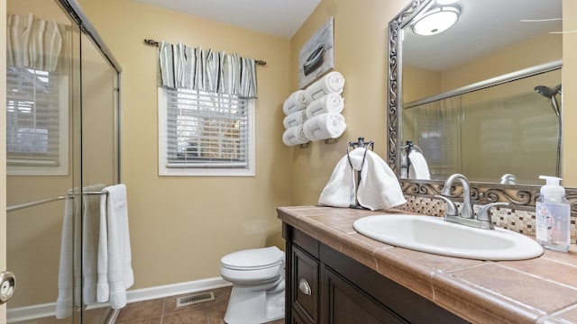 bathroom featuring tile patterned flooring, vanity, a shower with shower door, and toilet