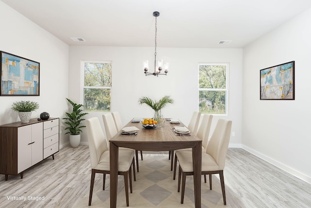 dining space with light hardwood / wood-style floors and a chandelier