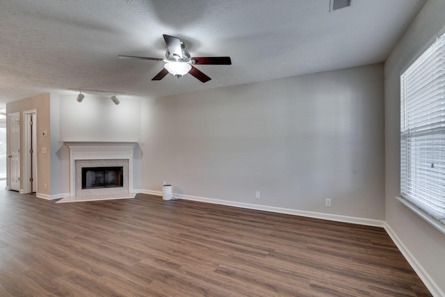 unfurnished living room featuring a fireplace, a textured ceiling, dark hardwood / wood-style flooring, and a healthy amount of sunlight