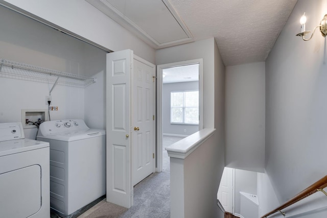 washroom with washing machine and dryer, light carpet, and a textured ceiling