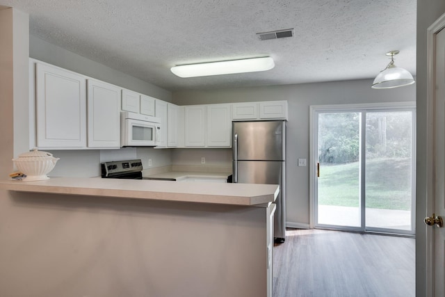 kitchen with decorative light fixtures, kitchen peninsula, range with electric cooktop, and stainless steel refrigerator