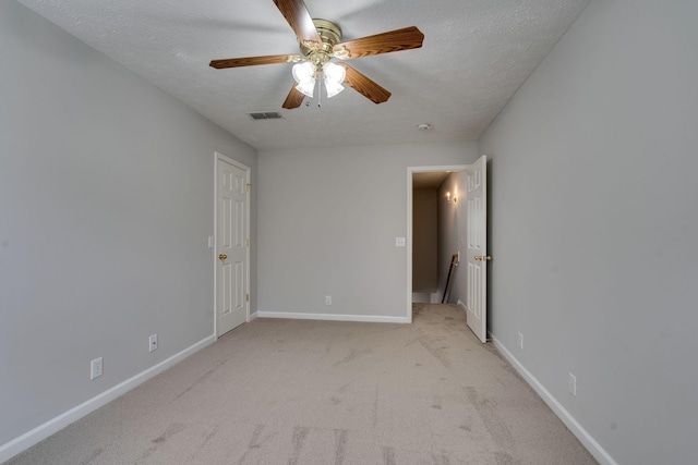 carpeted spare room featuring ceiling fan and a textured ceiling