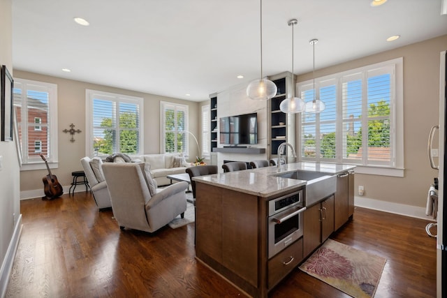 kitchen with oven, plenty of natural light, an island with sink, and decorative light fixtures