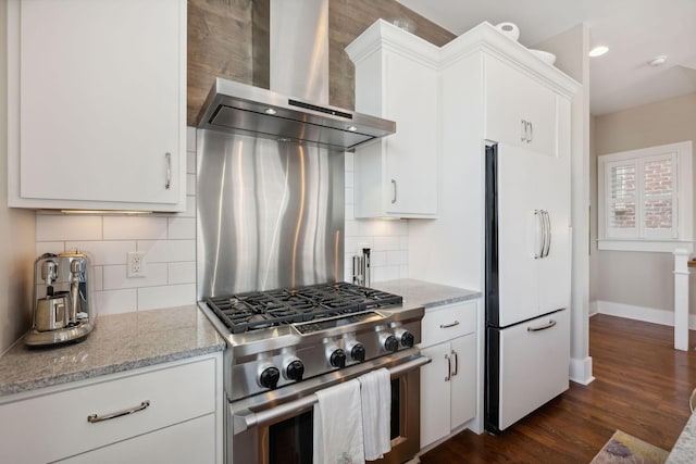 kitchen with white cabinets, white fridge, wall chimney range hood, and high end range