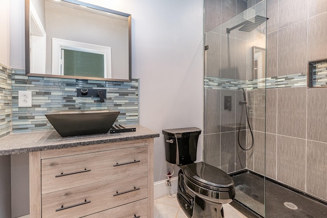 bathroom featuring vanity, backsplash, tile patterned floors, toilet, and tiled shower