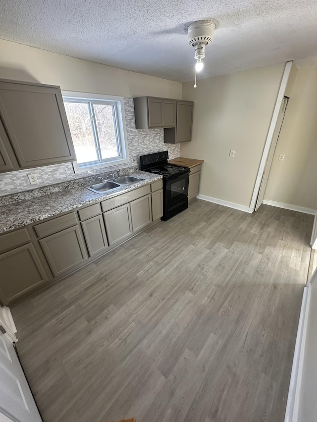 kitchen featuring tasteful backsplash, black range with electric stovetop, sink, and light wood-type flooring