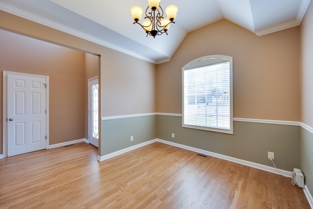 unfurnished room featuring a notable chandelier, light hardwood / wood-style floors, lofted ceiling, and ornamental molding