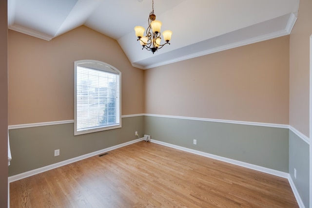 empty room with a chandelier, hardwood / wood-style floors, crown molding, and lofted ceiling