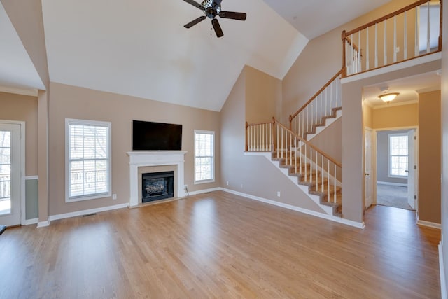 unfurnished living room with light wood-type flooring, plenty of natural light, ceiling fan, and ornamental molding