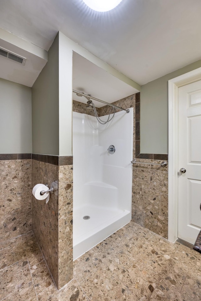 bathroom with walk in shower and tile walls