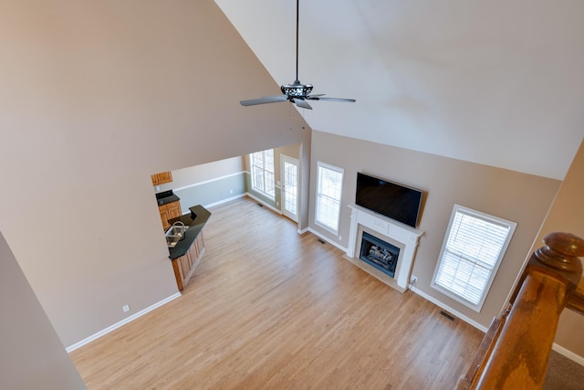 living room with ceiling fan, high vaulted ceiling, and light wood-type flooring