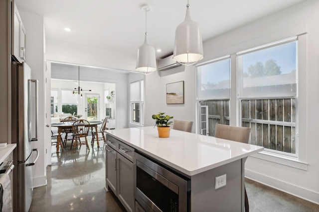 kitchen featuring pendant lighting, plenty of natural light, a kitchen island, and appliances with stainless steel finishes