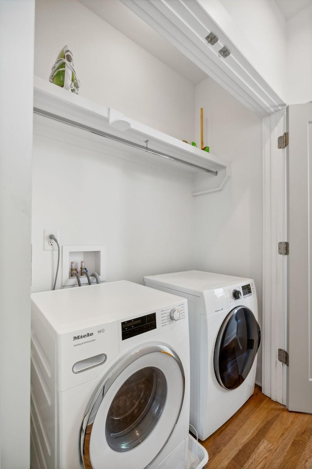 clothes washing area with washer and dryer and light hardwood / wood-style flooring