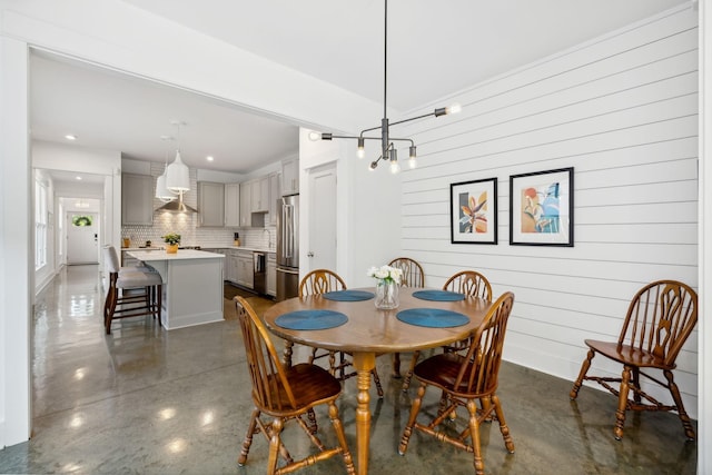 dining area with an inviting chandelier and wood walls