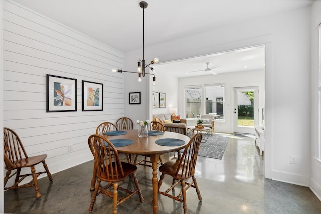 dining area with ceiling fan with notable chandelier and wooden walls