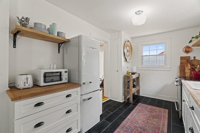 kitchen featuring white cabinets, white appliances, and butcher block countertops