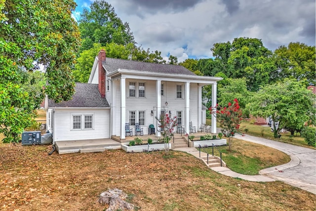 greek revival inspired property featuring a front lawn and a porch