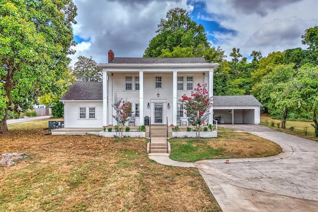 view of front facade featuring an outbuilding, a porch, a garage, and a front lawn