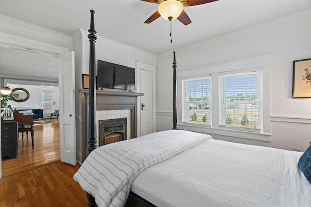 bedroom featuring a tile fireplace, ceiling fan, dark hardwood / wood-style flooring, and ornamental molding