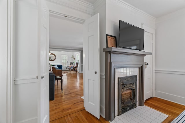 living room with crown molding, a fireplace, and light hardwood / wood-style flooring