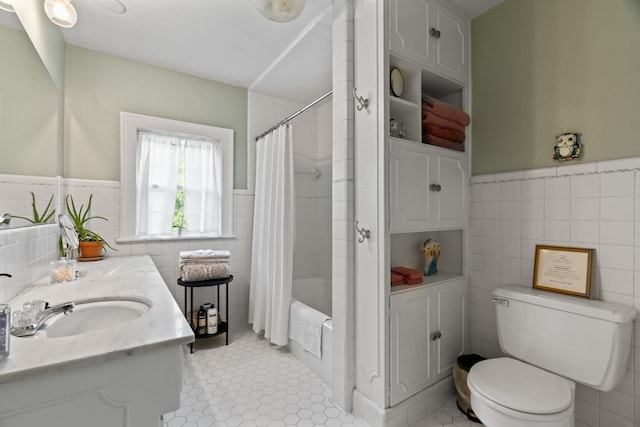 full bathroom featuring shower / tub combo, tile patterned flooring, toilet, vanity, and tile walls