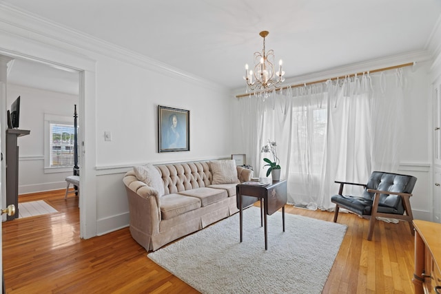 living room featuring light hardwood / wood-style flooring, a notable chandelier, and crown molding