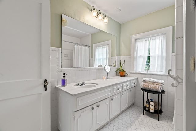 bathroom with tile patterned flooring, vanity, tile walls, and walk in shower