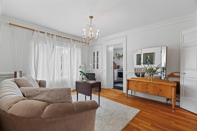 living room featuring wood-type flooring, crown molding, and a chandelier