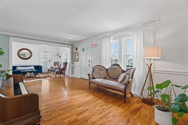 living room featuring a healthy amount of sunlight, light hardwood / wood-style floors, and crown molding