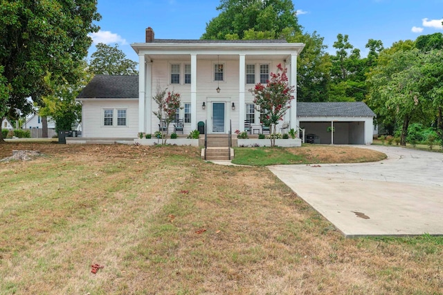 view of front of property featuring covered porch, a garage, an outbuilding, and a front lawn